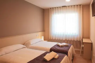 a hotel room with two beds and a window at Hotel La Puerta de Arzúa in Arzúa