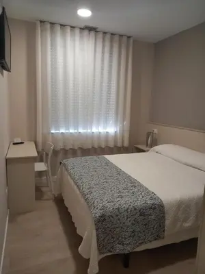 a bedroom with a bed and a desk and a window at Hotel La Puerta de Arzúa in Arzúa