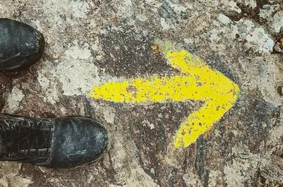 a persons shoe and a yellow arrow on the ground at Hotel La Puerta de Arzúa in Arzúa
