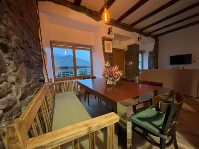 a dining room with a table and a stone wall at Casa Osu Pardo VuT in Caboalles de Abajo