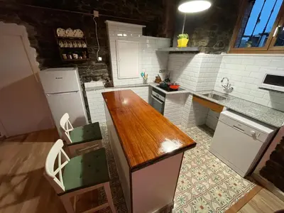 a kitchen with white appliances and a wooden counter top at Casa Osu Pardo VuT in Caboalles de Abajo