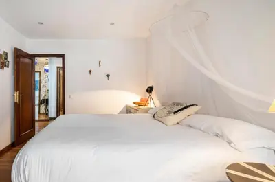 a white bedroom with a large white bed with curtains at Lujoso y amplio piso con 5 habitaciones in Santiago de Compostela