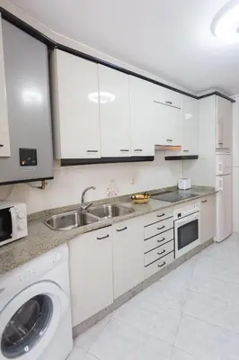 a white kitchen with a sink and a washing machine at Casa Goros I in Melide
