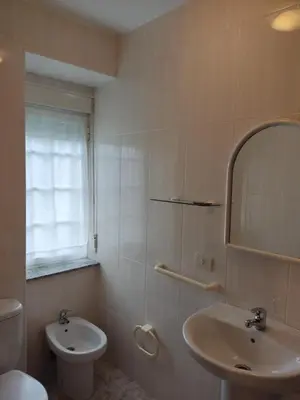 a white bathroom with a toilet and a sink at OS MUIÑOS in Ribadeo