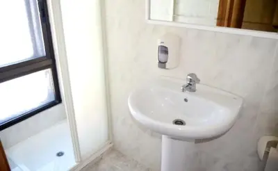 a white bathroom with a sink and a shower at Pensión Carballeira in Arzúa