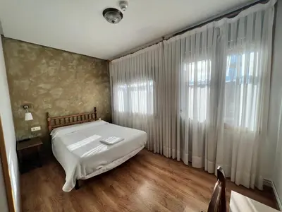 a bedroom with a bed and a large window at Pensión Carballeira in Arzúa