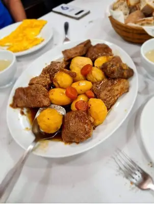 a plate of food with meat and vegetables on a table at Pensión Carballeira in Arzúa