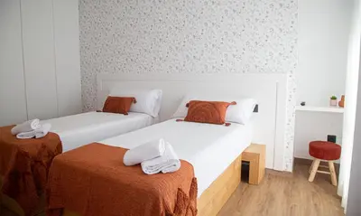 a bedroom with two beds and a chair at Pensión Praza das Coles in Melide