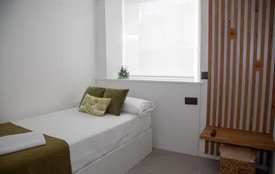 a small bedroom with a bed and a window at Pensión Praza das Coles in Melide