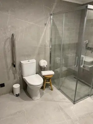 a bathroom with a toilet and a glass shower at Pensión Praza das Coles in Melide