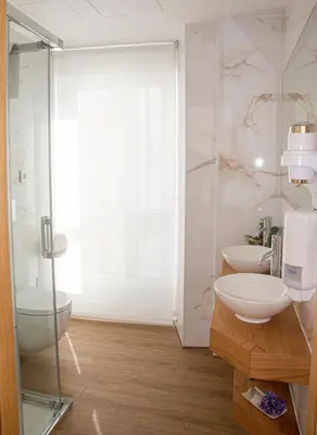 a bathroom with two sinks and a glass shower at Pensión Praza das Coles in Melide