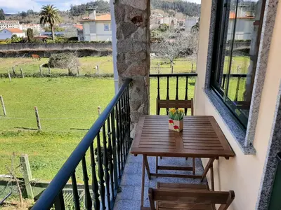 a wooden table on a balcony with a view of a field at Apartamento AS CARBALLAS in Caldas de Reis