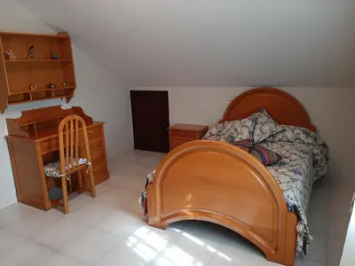 a bedroom with a bed with a wooden headboard and a chair at Apartamento AS CARBALLAS in Caldas de Reis
