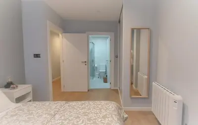 a white bedroom with a bed and a bathroom at Avante24 in Puentedeume