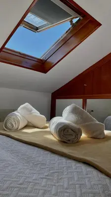 two towels are sitting on a bed with a skylight at Alfonso Vll in Caldas de Reis