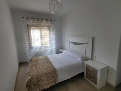 a white bedroom with a bed and a window at Piso termal III in Ourense