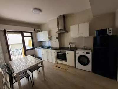 a small kitchen with a table and a refrigerator at Piso termal III in Ourense