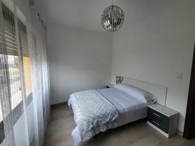 a white bedroom with a bed and a window at Piso termal III in Ourense