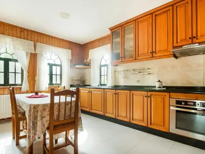 a large kitchen with wooden cabinets and a table with a table at Apartment near Santiago de Compostela in Eirapedriña