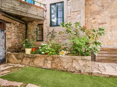 a stone house with a retaining wall with plants at Apartment near Santiago de Compostela in Eirapedriña