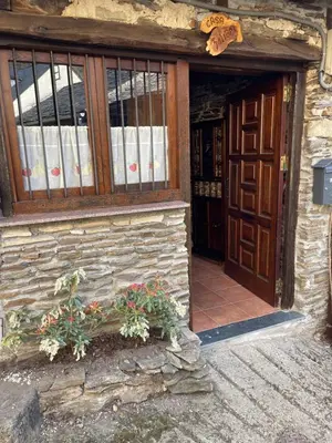 an entrance to a stone building with a window and flowers at Casa Folibar in Manzanedo de Valdueza