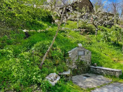 a small stone structure on a hill with a tree at Casa Folibar in Manzanedo de Valdueza
