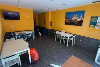 a room with tables and chairs and a yellow wall at Albergue Lecer Sobrado in Porta