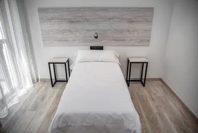 a white bed in a room with two side tables at Hotel Chips Fene in Fene