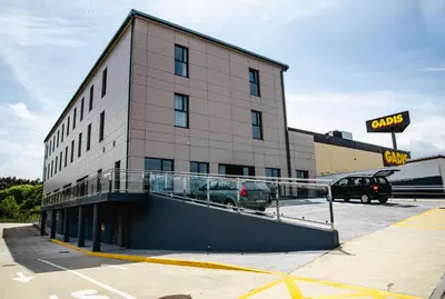 a building with a car parked in a parking lot at Hotel Chips Fene in Fene