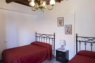 a bedroom with two beds with red sheets and a chandelier at A Pousa Pensión rural (Camino de Santiago Sanabrés) in Armariz
