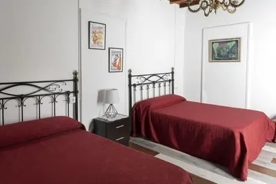 a bedroom with two beds with red sheets and a lamp at A Pousa Pensión rural (Camino de Santiago Sanabrés) in Armariz