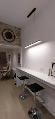 a kitchen with a counter with stools and a clock at O Berce Padrón casa rural in Padrón