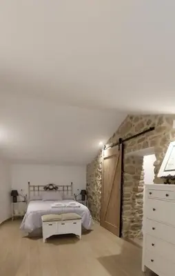 a bedroom with a bed and a stone wall at O Berce Padrón casa rural in Padrón