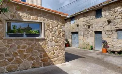 a stone building with a window with potted plants in it at O Berce Padrón casa rural in Padrón