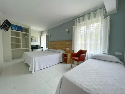a bedroom with two beds and a chair and a window at Grupo Las Catedrales - Hotel Amadora in Barreiros