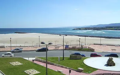 a parking lot with cars parked on the beach at Apartamento Marexada Foz in Foz