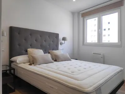 a large white bed in a white room with a window at Apartamentos Rey by Como en Casa in Santiago de Compostela