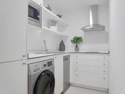 a white kitchen with a washing machine and a sink at Apartamentos Rey by Como en Casa in Santiago de Compostela