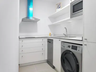 a white kitchen with a washing machine and a sink at Apartamentos Rey by Como en Casa in Santiago de Compostela