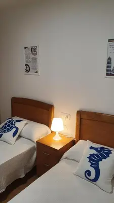 a bedroom with two beds and a lamp on a night stand at Os Castelos Playa de Covas in Viveiro