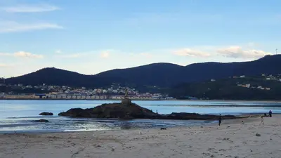 a beach with a small island in the water at Os Castelos Playa de Covas in Viveiro