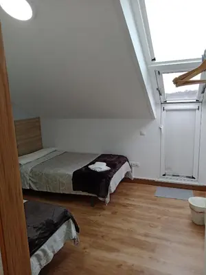 a bedroom with two beds and a large window at Pension Ameneiral in O Pedrouzo