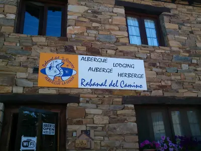 a building with signs on the side of it at Albergue La Senda in Rabanal del Camino