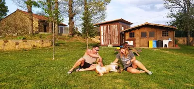three people sitting in the grass with a dog at Albergue La Senda in Rabanal del Camino