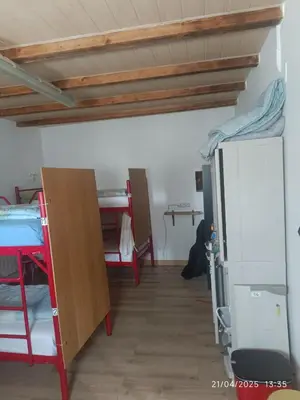 a room with several bunk beds and a refrigerator at Albergue La Senda in Rabanal del Camino