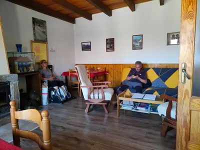 a man sitting on a couch in a living room at Albergue La Senda in Rabanal del Camino