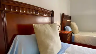 a bedroom with two beds and a wooden headboard at Apartamento Padrón Centro P3 by URent in Padrón