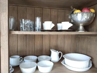 a shelf with white dishes and a bowl of fruit at Charming House in Parada with Large Garden in Parada