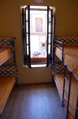 a room with three bunk beds and a window at Albergue de peregrinos Compostela in Molinaseca