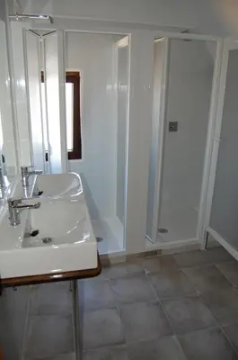 a white bathroom with a sink and a shower at Albergue de peregrinos Compostela in Molinaseca